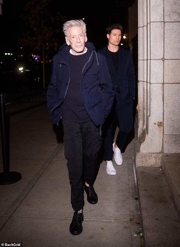 Calvin Klein, 83, steadies himself after a brief stumble outside The Brant Foundation in New York as cameras flash; partner Kevin Baker walks ahead.