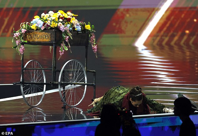 Latimer performs the staged fall while handing out flowers on stage before rising to reveal her gown