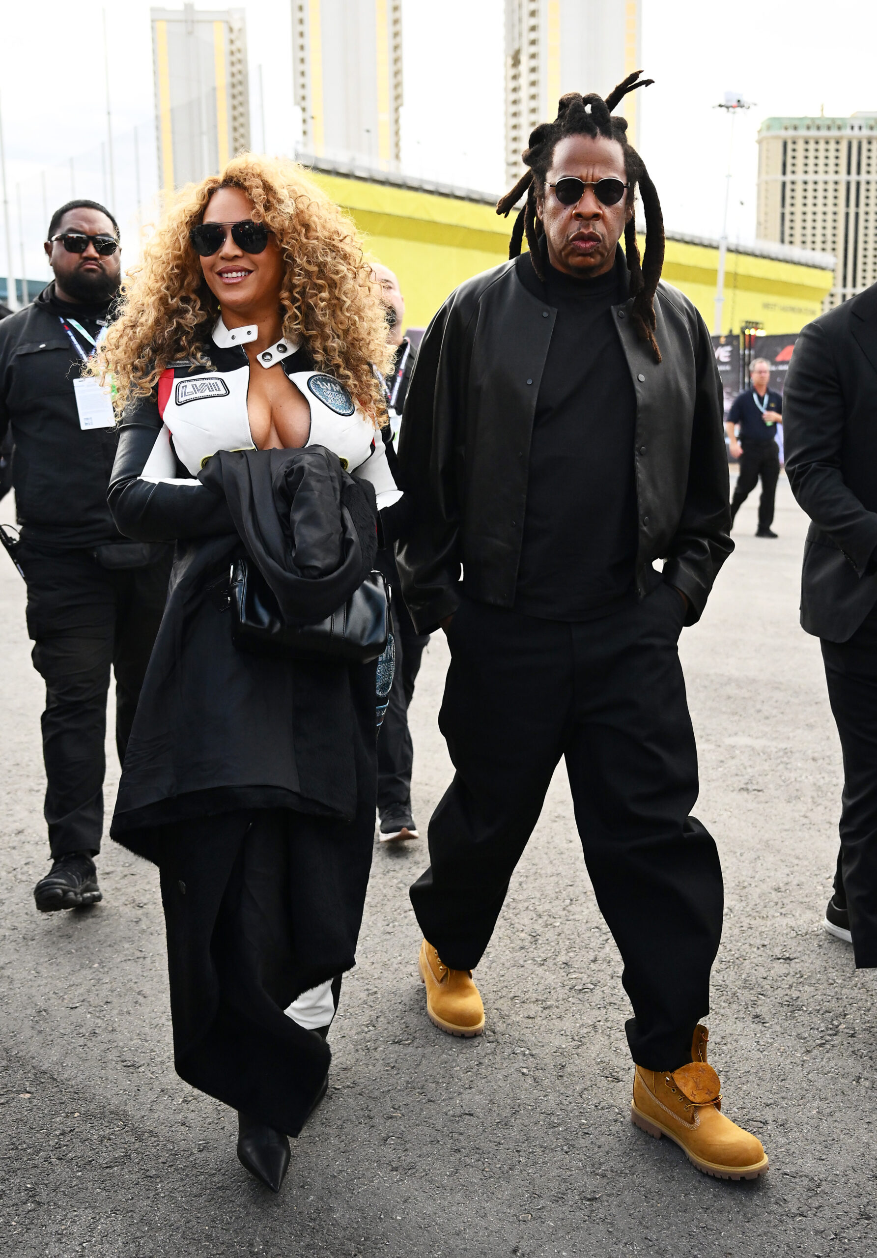 Jay-Z and Beyonce arrive arm in arm at the F1 Grand Prix of Las Vegas; she wears the racing suit and he wears an all-black look with a collarless leather jacket.