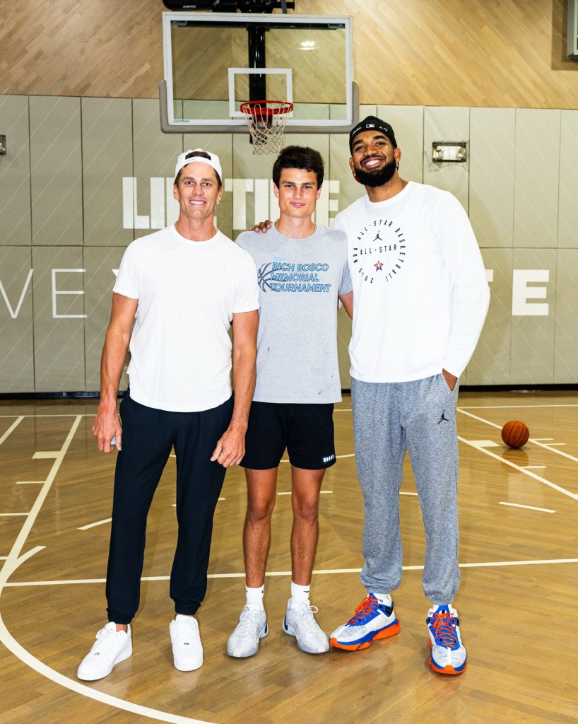 Tom Brady, his son Jack, and Karl-Anthony Towns standing on a basketball court.