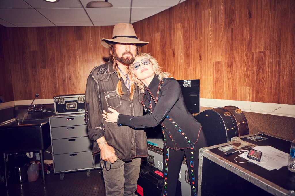 Billy Ray Cyrus and Miley Cyrus hugging backstage.