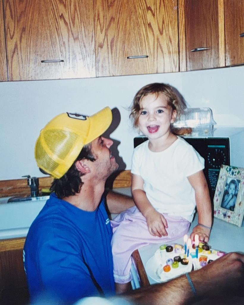 Paul Walker looks up at young Meadow as she smiles from the kitchen counter beside a birthday cake.