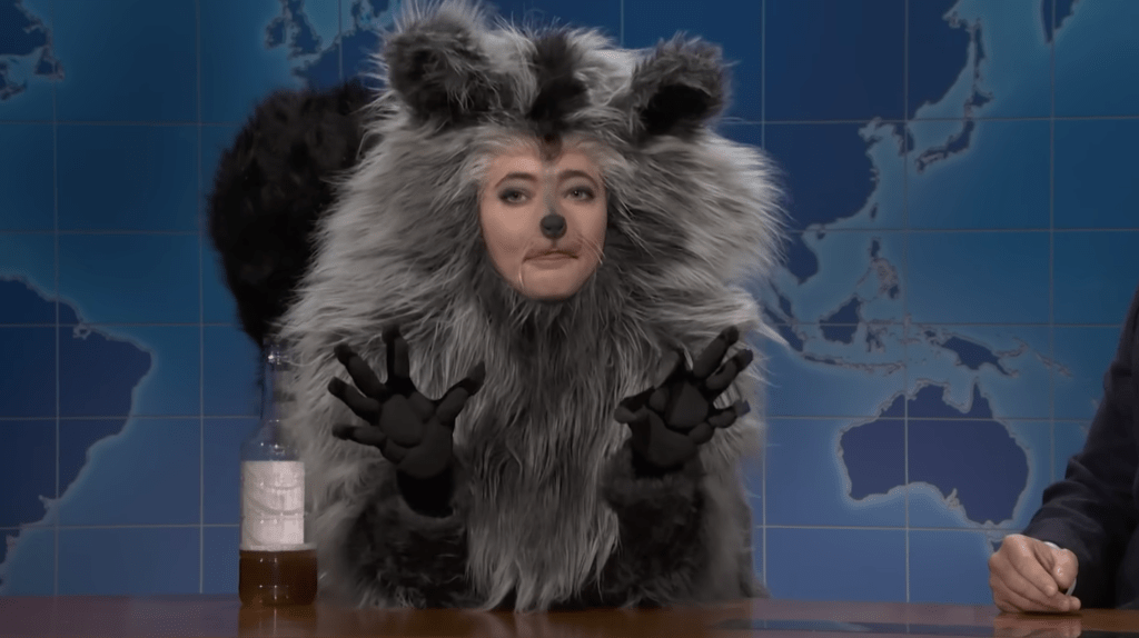 Sarah Sherman in a raccoon costume on SNL's Weekend Update, holding a bottle.