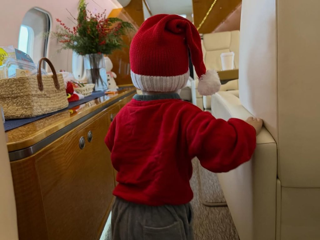 Justin Bieber's son Jack, 16 months, in a Santa hat and red sweater walking on a decorated private jet.