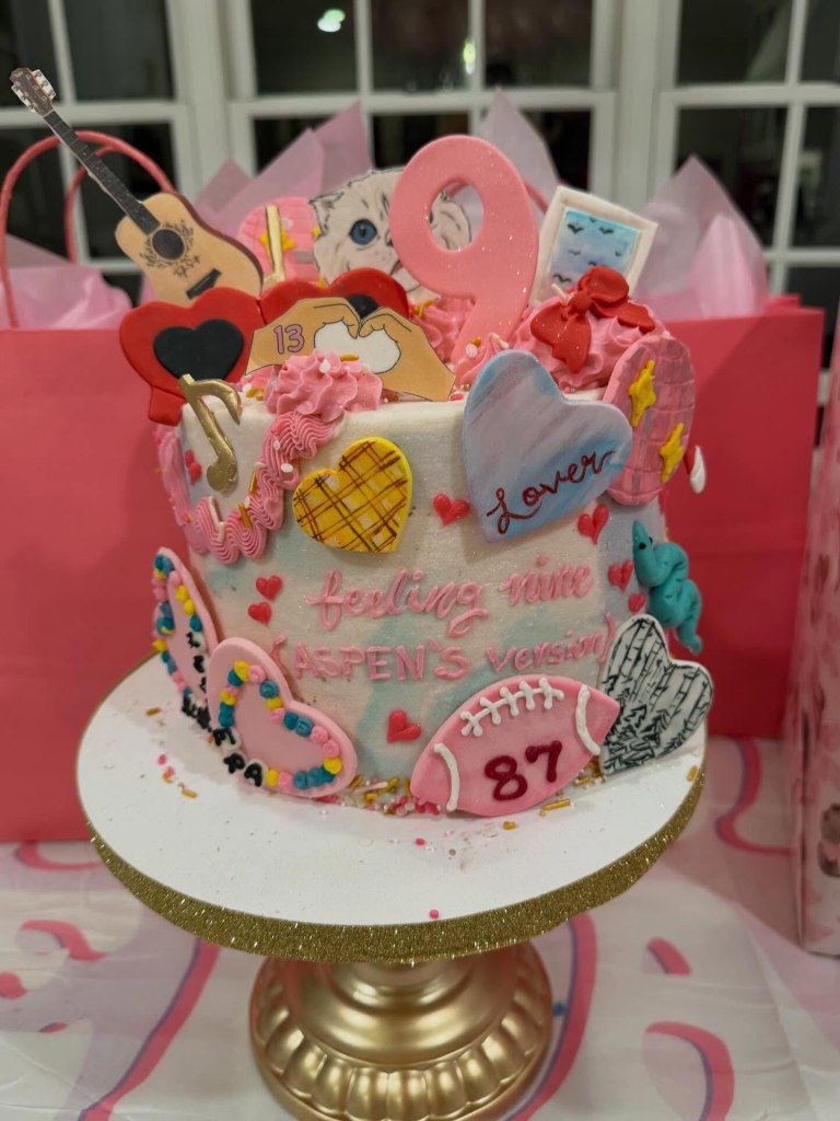 Taylor Swift-themed birthday cake with cookies including a pink 9, guitar, hearts, and a Travis Kelce 87 football.