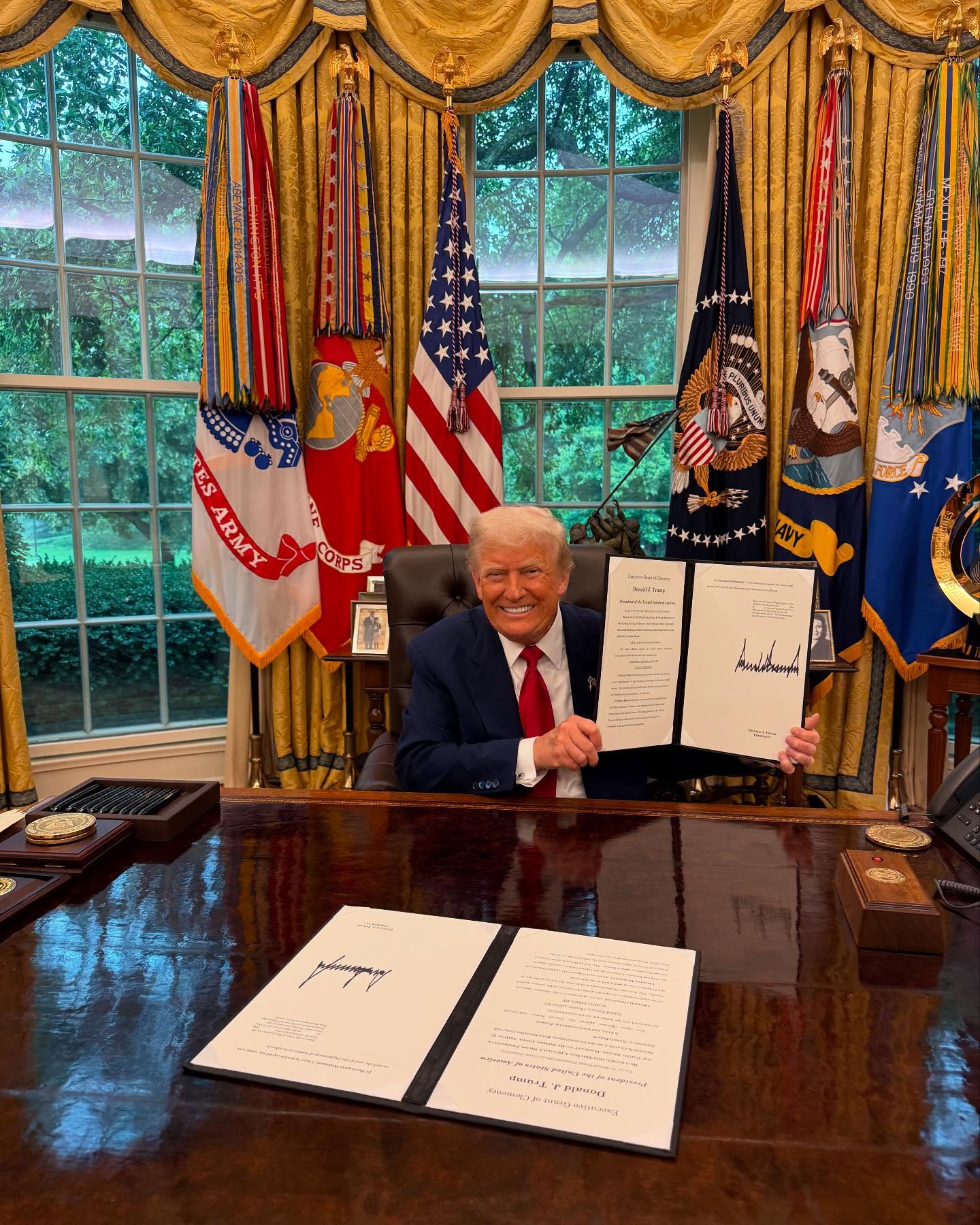 Donald Trump holds an Executive Grant of Clemency document.