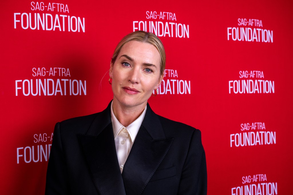 Actress Kate Winslet poses in front of a red backdrop with the SAG-AFTRA Foundation logo repeated.