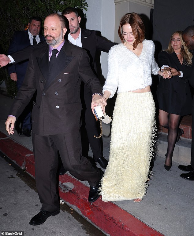 Emma Stone in a fuzzy white cardigan and long cream skirt