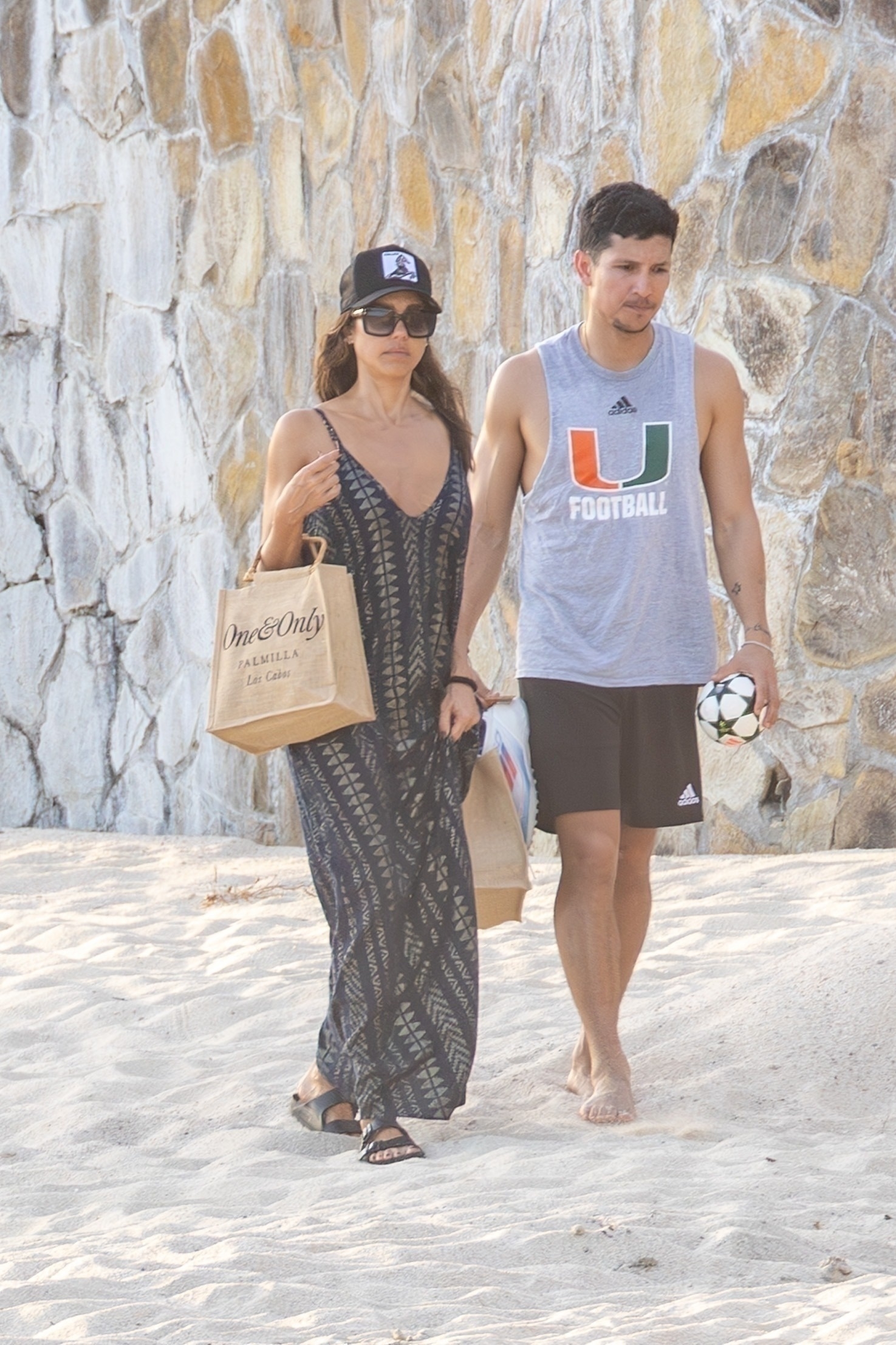 Jessica Alba and Danny Ramirez holding hands while walking on the beach in Cabo.