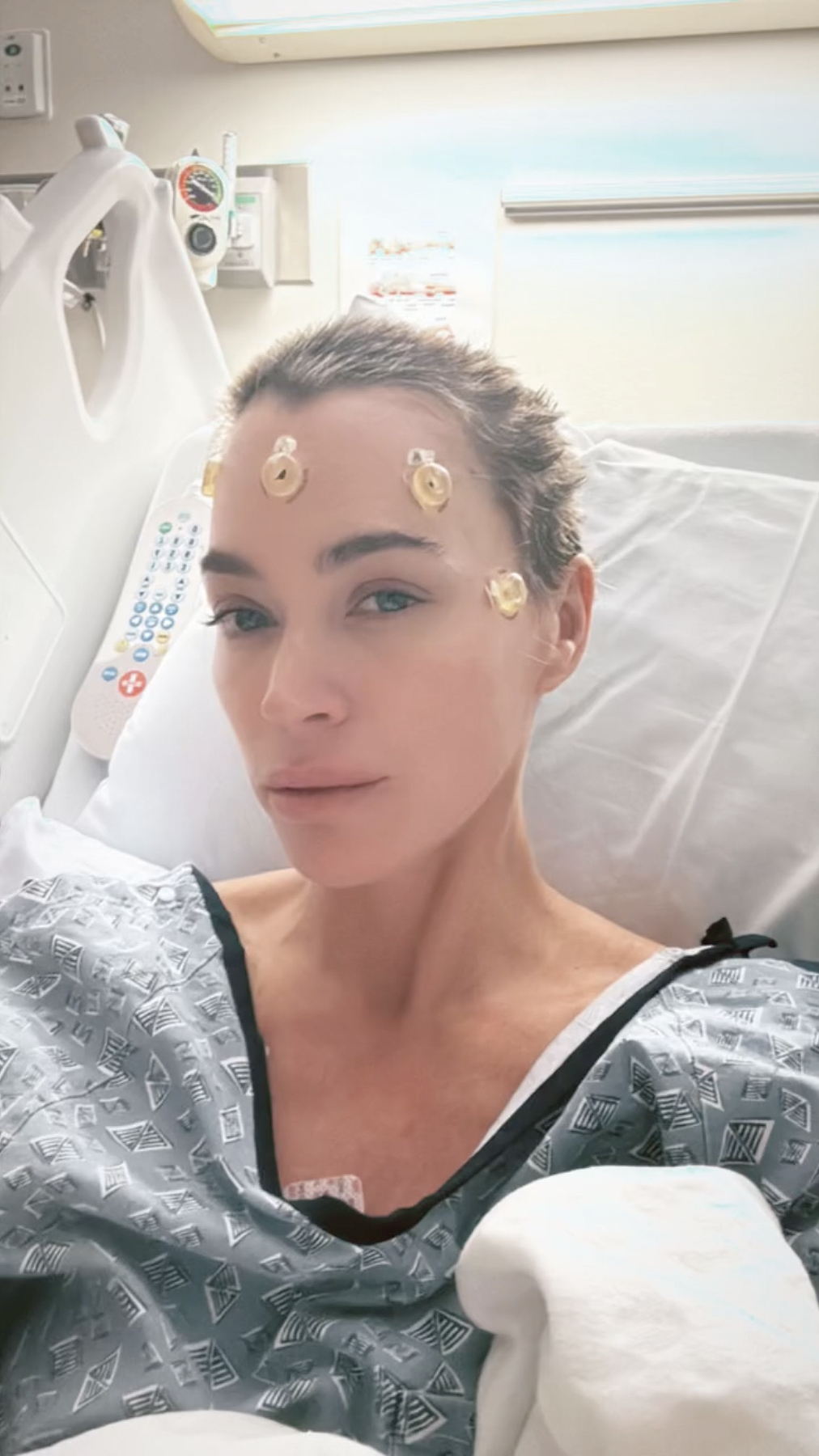 Teddi Mellencamp in a hospital bed with medical sensors on her forehead.