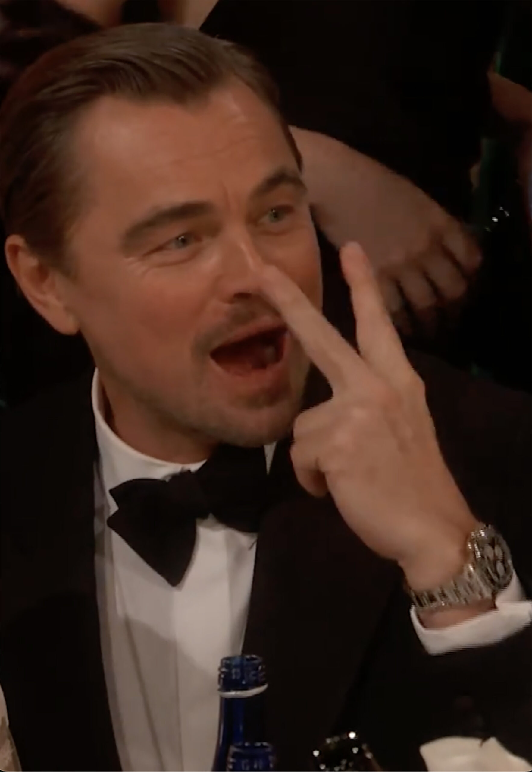Leonardo DiCaprio making a "peace sign" gesture towards his nose.