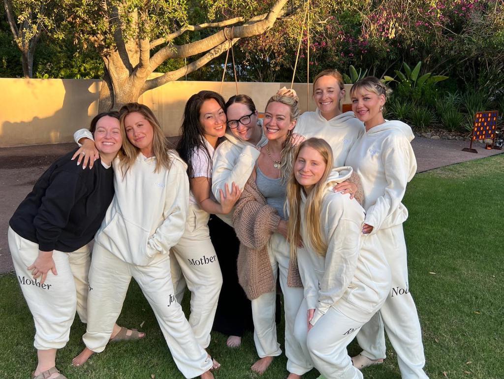 Ashley Tisdale and Hilary Duff pose with a group of women in matching loungewear.