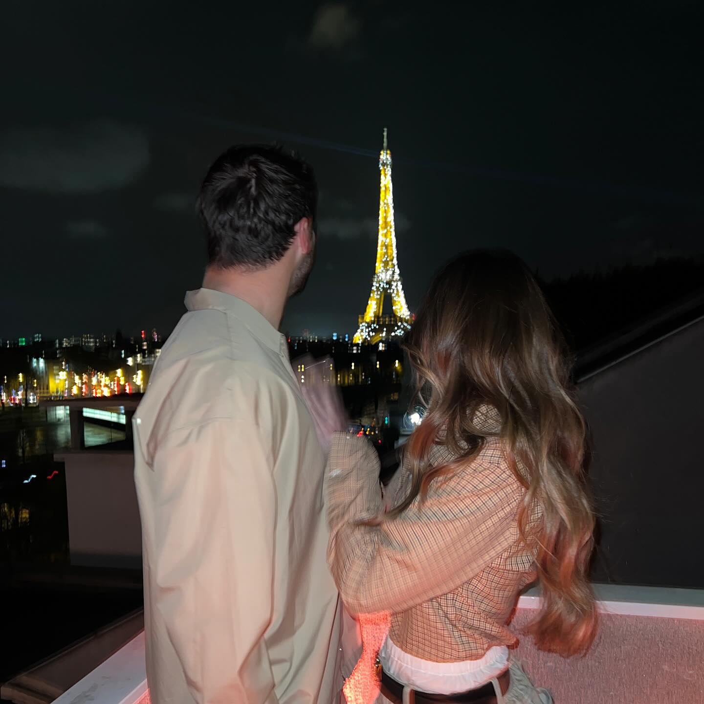 Hailee Steinfeld and Josh Allen overlooking the Eiffel Tower at night.