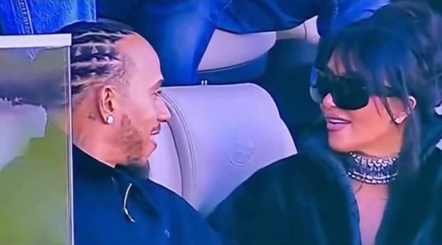 Close-up of Kim Kardashian and Lewis Hamilton appearing cozy in a private Super Bowl suite; her black faux-fur jacket and his diamond earring visible.