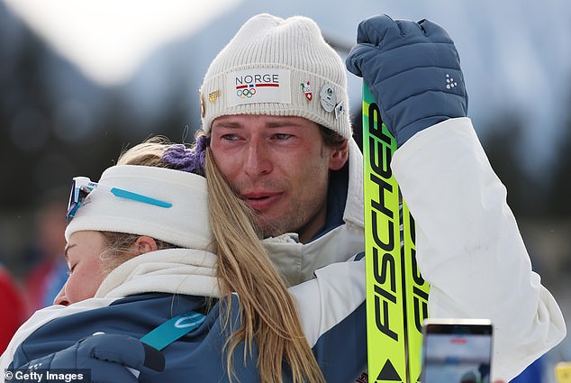 Sturla Holm Lgreid is embraced by Norwegian teammate Ingrid Landmark Tandrevold after his Olympic race in Milan-Cortina.