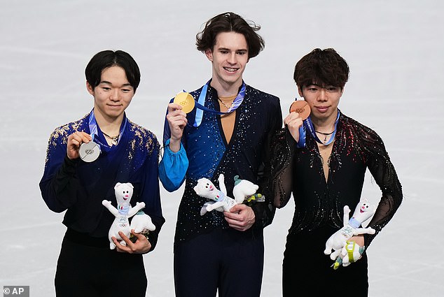 Mikhail Shaidorov (center) celebrates gold with Yuma Kagiyama (left, silver) and Shun Sato (right, bronze) on the podium.