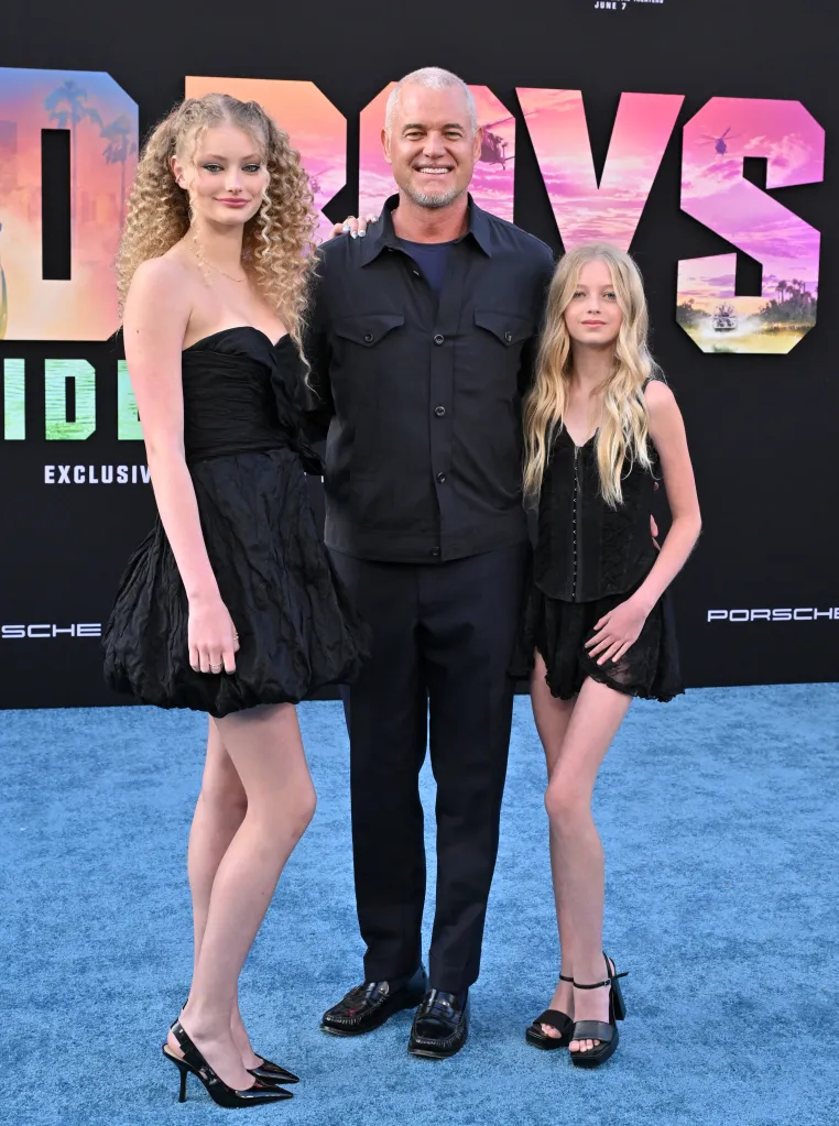 Eric Dane poses with daughters Billie Beatrice Dane and Georgia Geraldine Dane on a blue carpet.