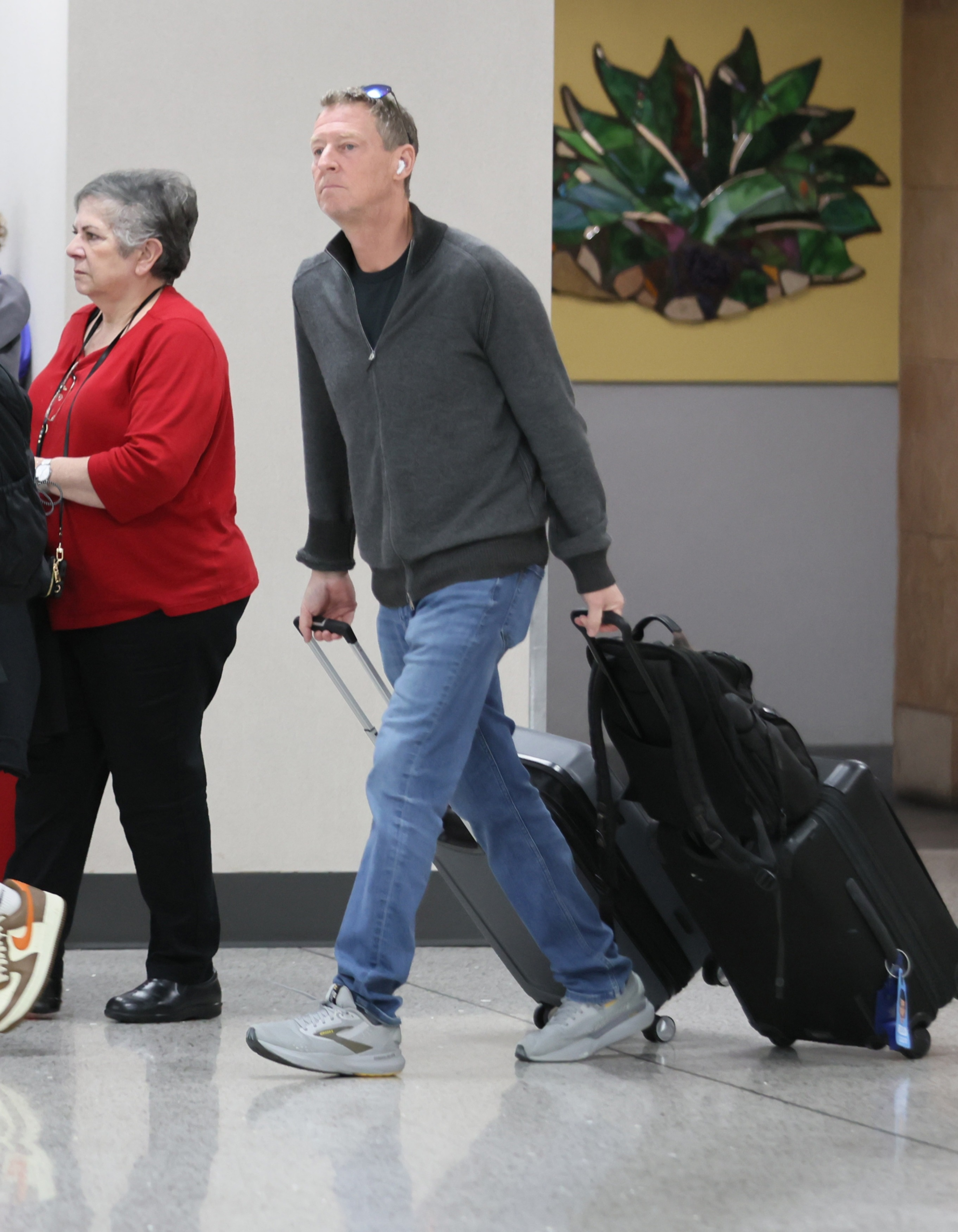 Michael Feldman walking through Tucson International Airport with carry-on luggage amid the search for his mother-in-law, Nancy Guthrie.