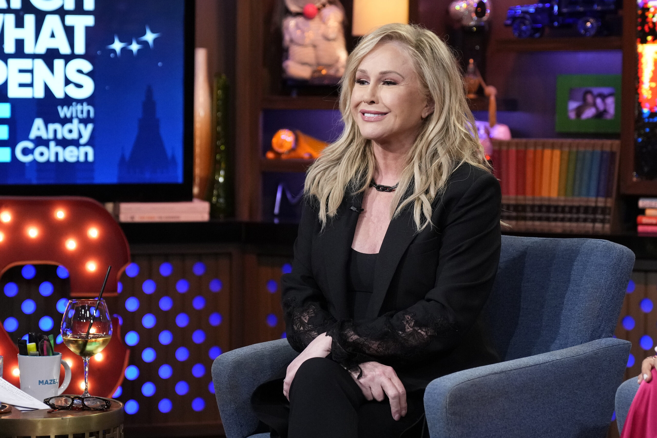 Kathy Hilton smiles while sitting in a blue chair during a talk show appearance.