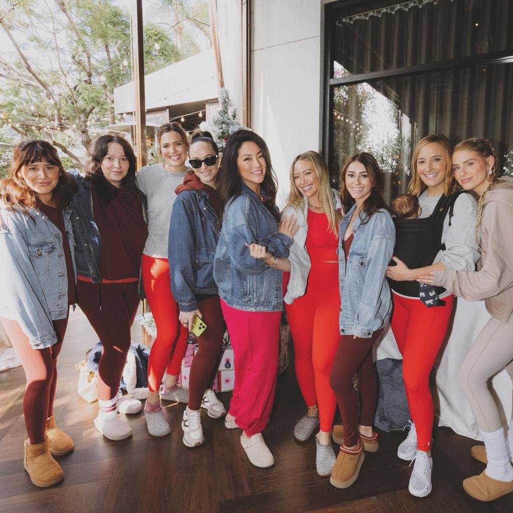 Ashley Tisdale with a group of mom friends in athletic wear, including one holding a baby.