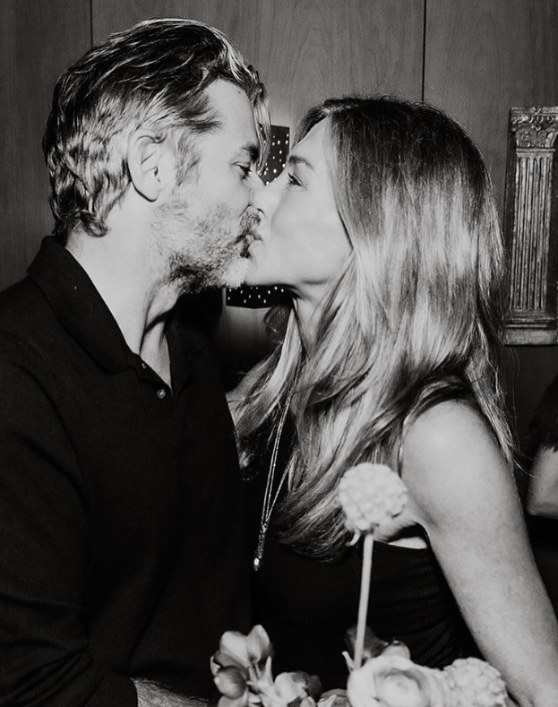 Jennifer Aniston and Jim Curtis share a black-and-white birthday kiss over a floral arrangement in his Instagram tribute.