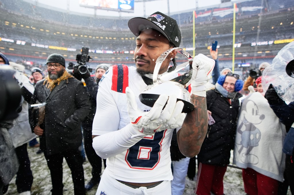 Stefon Diggs celebrating with the AFC Championship trophy in the snow.