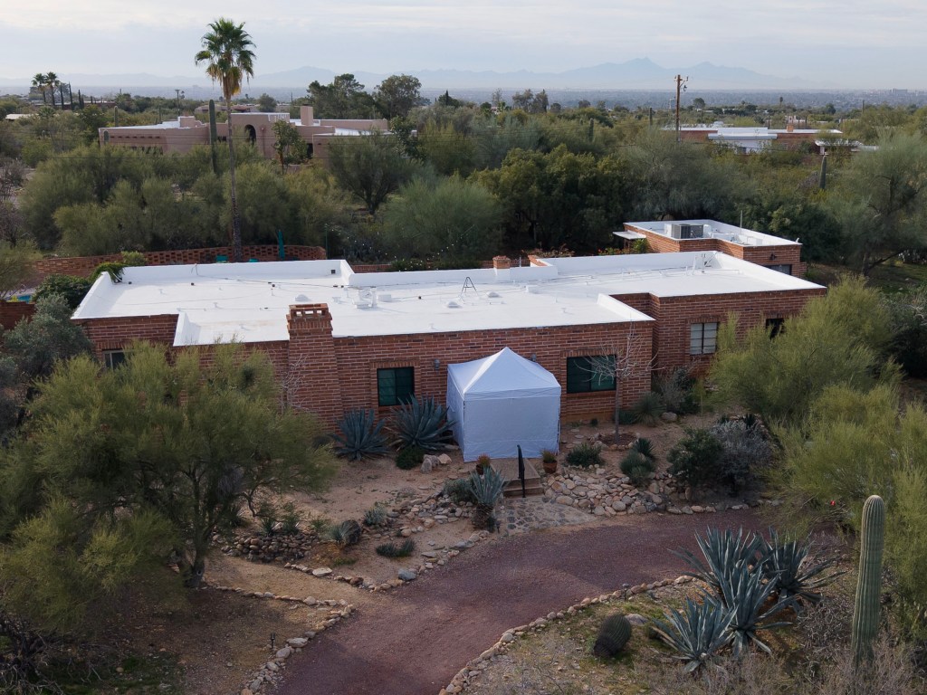 Drone view of a house in Tucson, AZ, with an FBI tent outside.