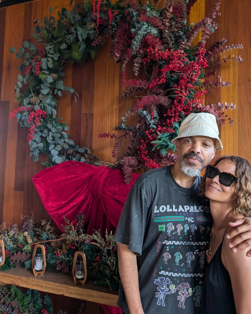 Halle Berry and Van Hunt embrace in front of a festive holiday wreath.