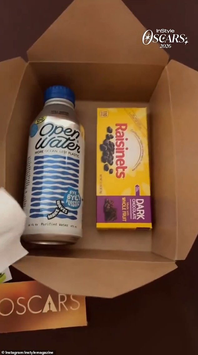 Oscars 2026 snack kit: bottled water, SkinnyPop popcorn, and dark chocolate Raisinets in a cardboard box