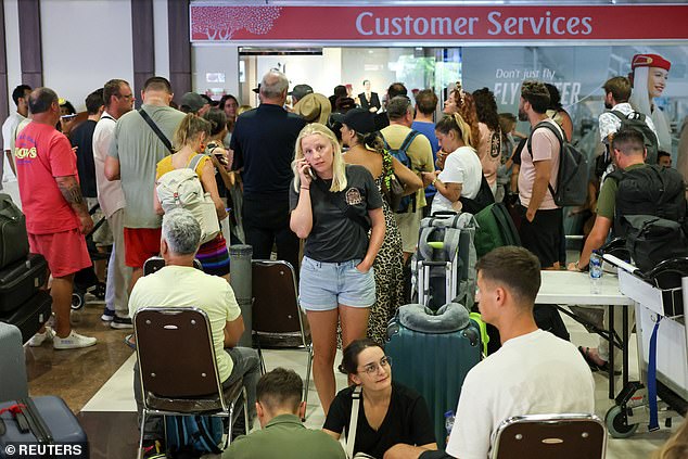Stranded passengers wait near an Emirates customer service desk after flights to Dubai, Doha, and Abu Dhabi were canceled.