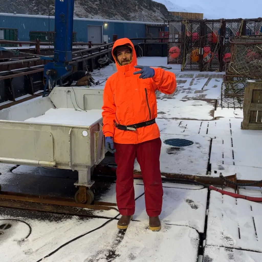 Todd Meadows poses on a snowy ship deck while working on a fishing boat.