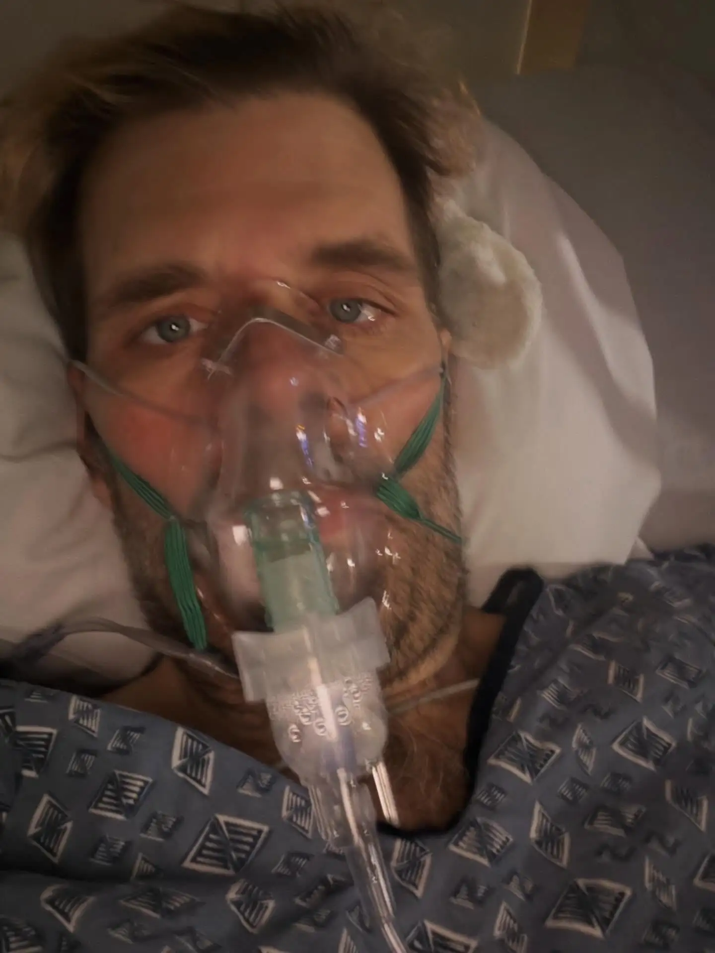 Perez Hilton in a hospital bed with an oxygen mask on his face.
