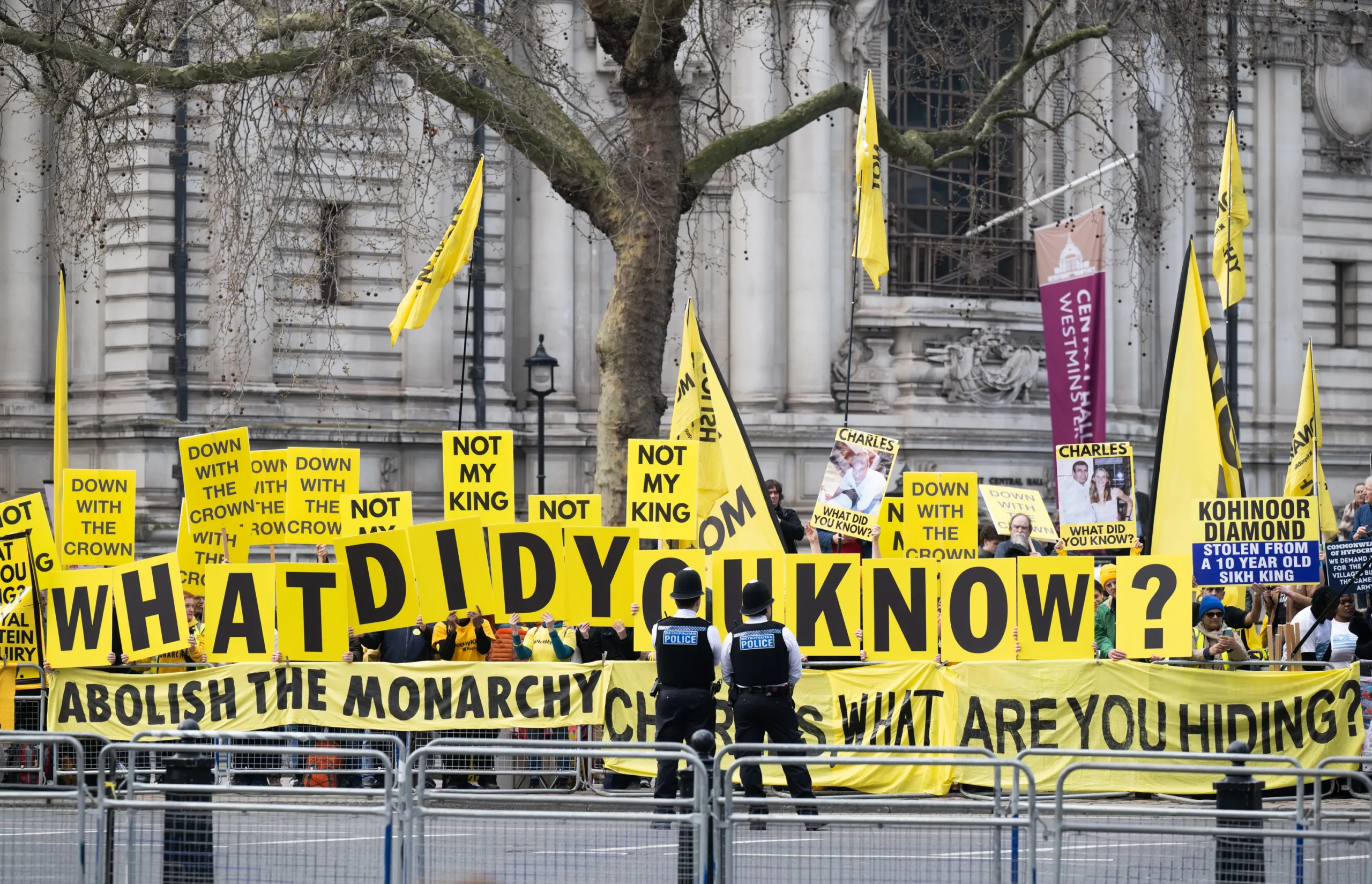 Protesters outside Westminster Abbey hold yellow "What did you know?" signs during the Commonwealth Day event.