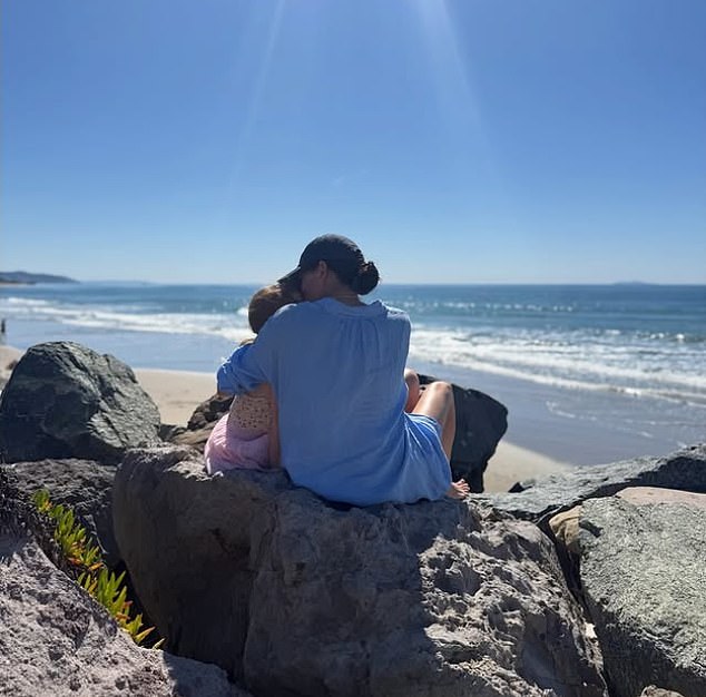 Meghan cuddles daughter Lilibet in a beachside photo shared on International Women's Day