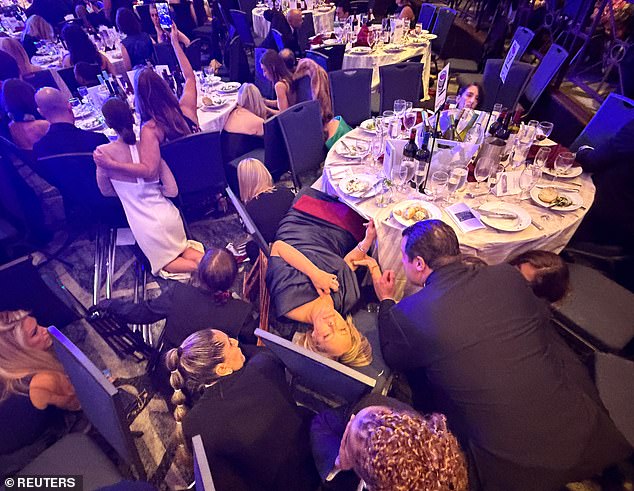 Attendees duck under tables at the Washington Hilton ballroom during the White House Correspondents' Dinner.