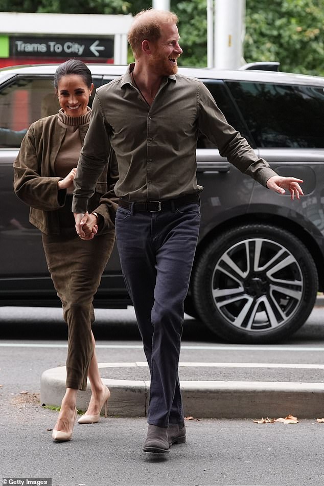 Meghan Markle and Prince Harry walking together during their Australia visit; outfits clearly visible amid public engagements.