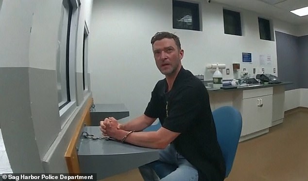 Justin Timberlake seated at a table in a police station after his June 2024 arrest in Sag Harbor, New York