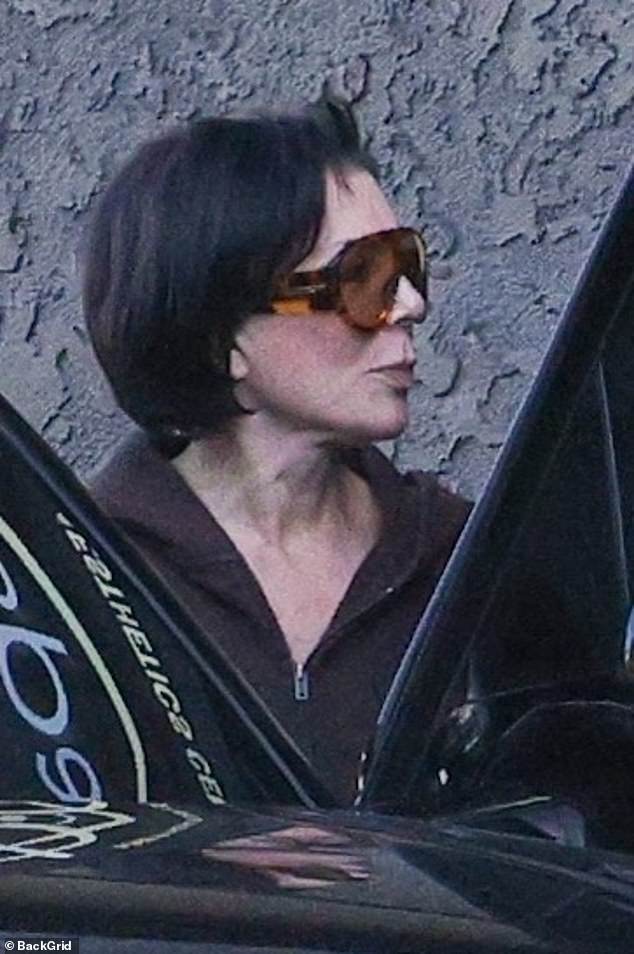 Kris Jenner leaves 7Q Spa Laser & Aesthetics in Los Angeles wearing sunglasses and a brown hoodie, with mildly flushed cheeks post-treatment.
