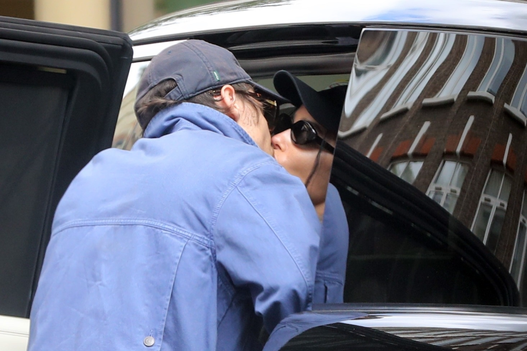 Harry Styles and Zoe Kravitz share a kiss in a candid moment; both wearing baseball caps and sunglasses.