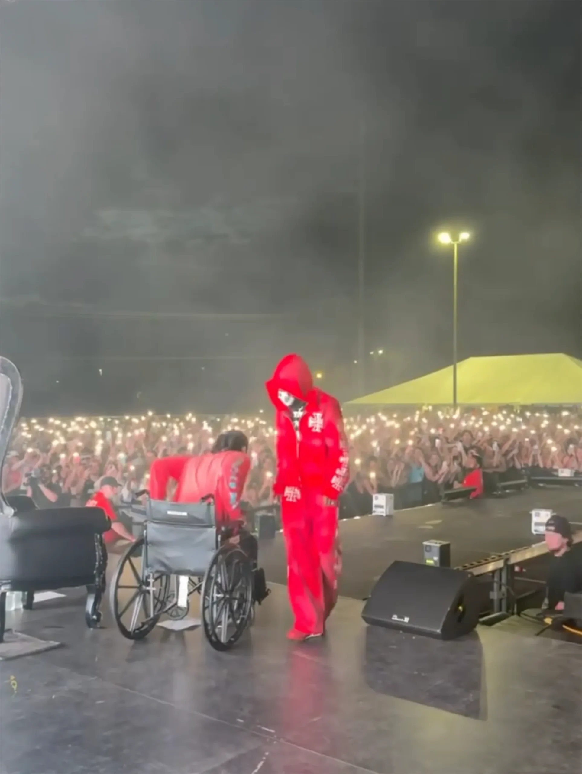 Offset performing on stage in a red tracksuit, with a wheelchair beside him.