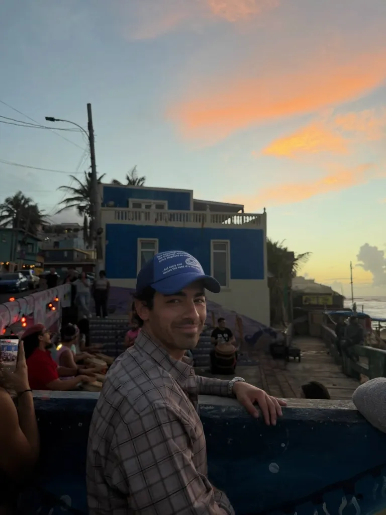 Joe Jonas wearing a blue cap and plaid shirt at sunset during his Puerto Rico getaway.