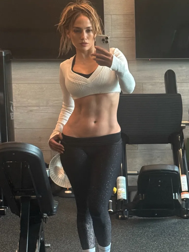 Jennifer Lopez poses for a mirror selfie in a gym, showing off her toned abs.