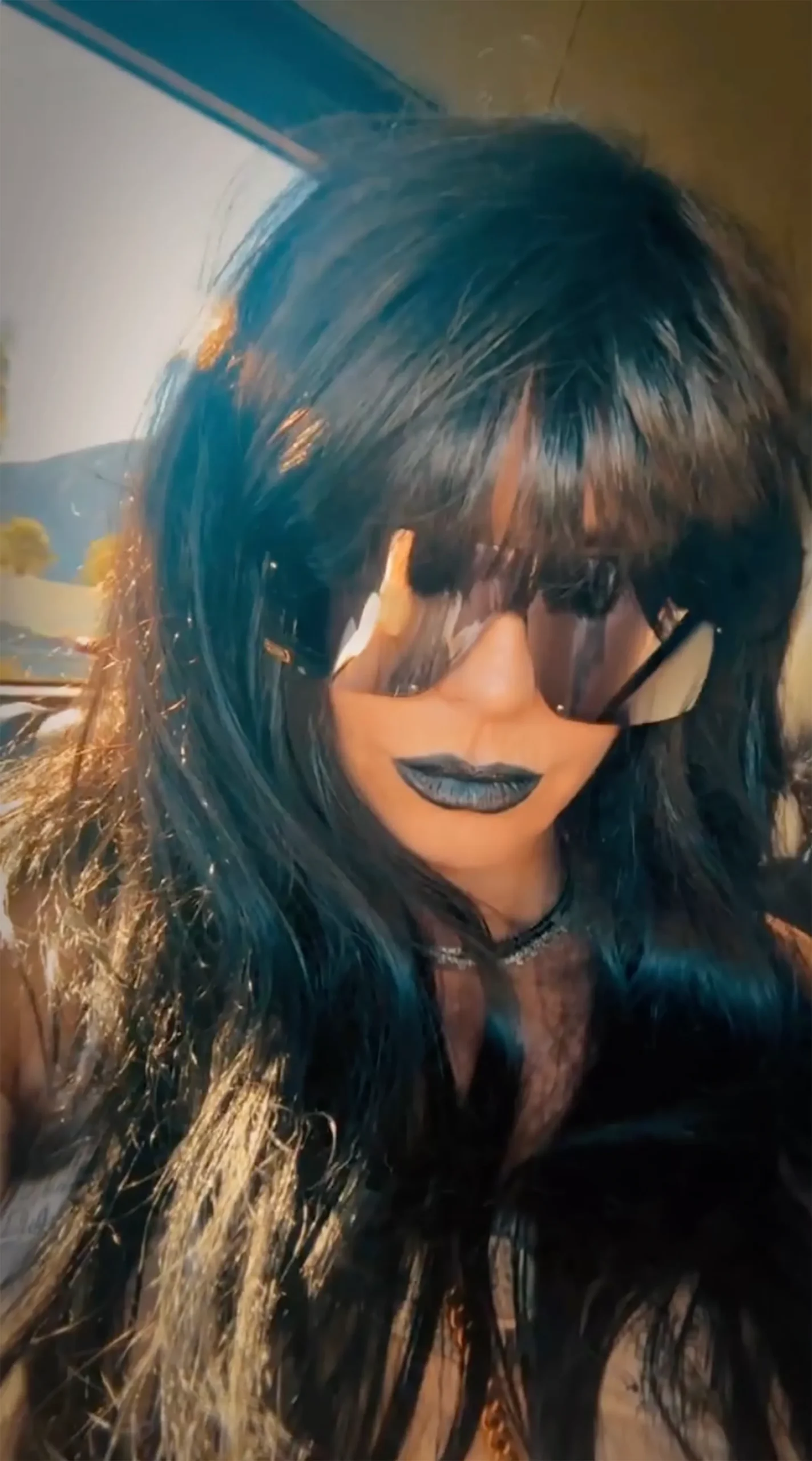 Close-up of Heidi Klum's 'Techno Hexen' disguise with black wig, oversized sunglasses, and black lipstick at Coachella.