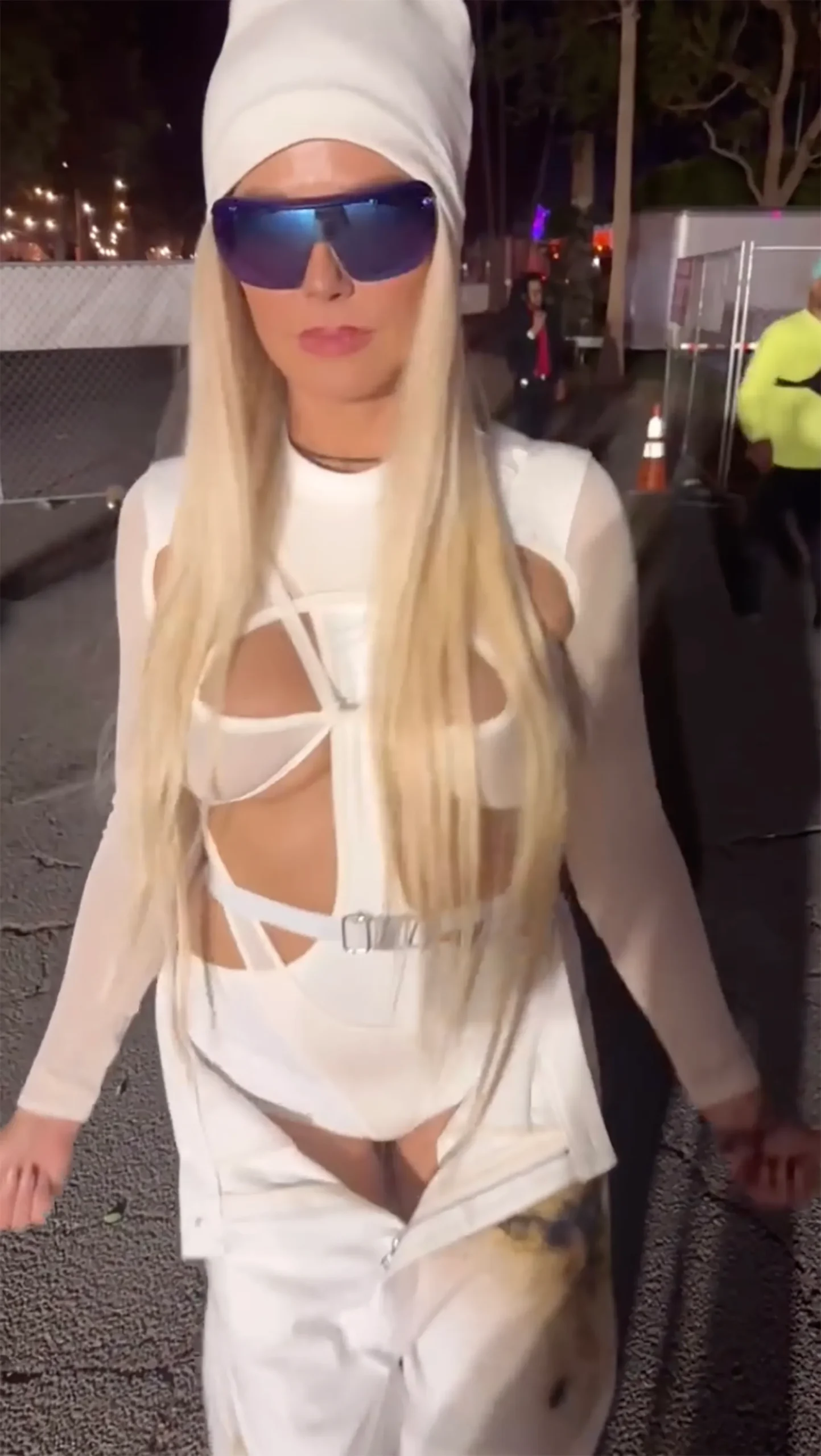 Heidi Klum's night-one all-white Coachella look with cutout bodysuit, matching pants, blue mirrored shades, and a white beanie.