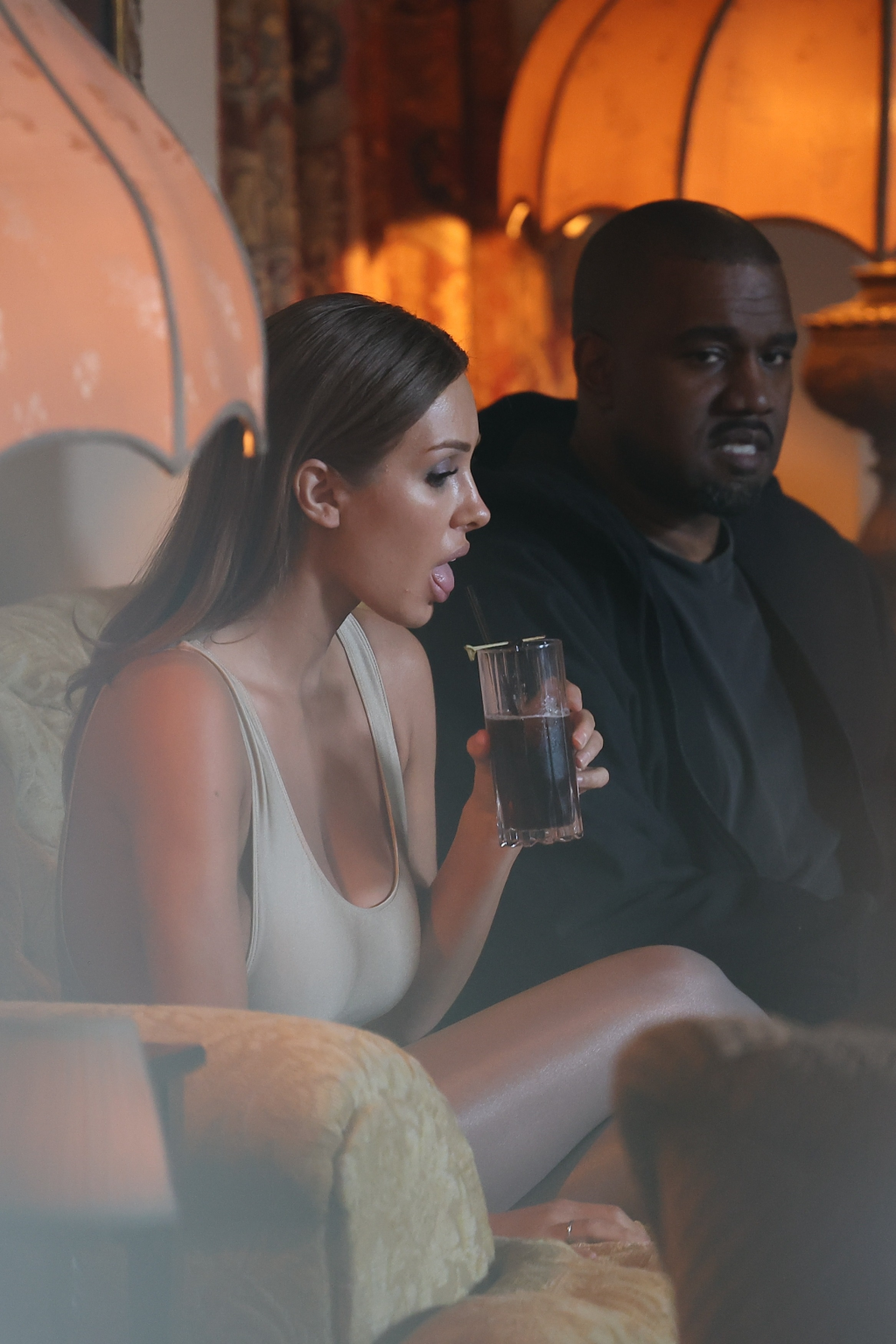 Bianca Censori sipping a drink beside Kanye West at Chateau Marmont.